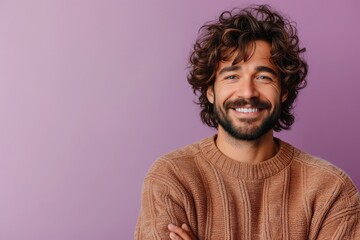 medium shot of a young cheerful man with beard and curly brown hair, arms crossed, brown sweater, in front of a purple background, copy space