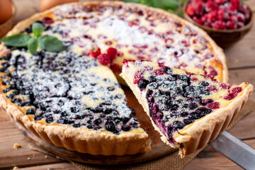 Fresh homemade forest fruits pie with wild fresh blueberries and raspberries on a wooden table