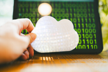 A person holds a symbol of a cloud, which indicates the cloud computing system and the data in it.