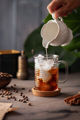 Cold coffee with ice in a glass cup on a wooden background - obrazy, fototapety, plakaty