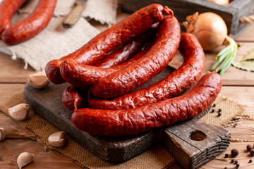 Smoked sausage on a wooden table with addition of fresh aromatic herbs and spices, natural product from organic farm, produced by traditional methods