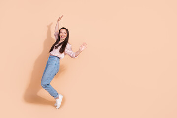 Fototapeta na wymiar Full size photo of funny carefree woman dressed silk blouse stand tiptoes near offer empty space isolated on beige color background