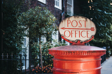 Red post box with a retro Post Office sign in London, UK.