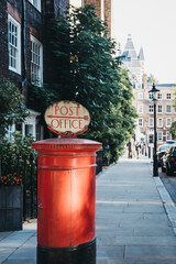 Fototapeta na wymiar Red post box with a retro Post Office sign in London, UK.