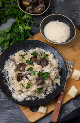 Risotto with mushrooms, parsley and parmesan on a dark background. View from above.