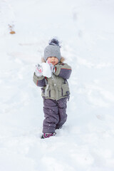 Fototapeta na wymiar Baby enjoys winter playing snowballs