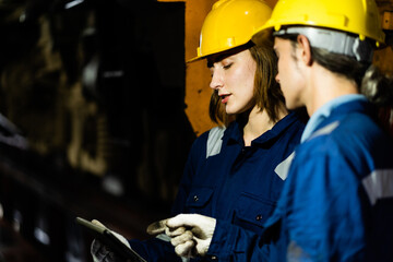 A team of young professional railway engineers wearing hard hats and protective suits inside a...