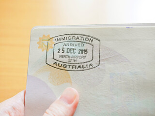 Hand holding passport with Australian immigration stamp