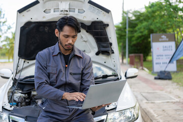 maintenance concept Asian auto mechanic or smith writing on clipboard at warehouse workshop Technician making checklist for car repair Roadside breakdown and insurance concept