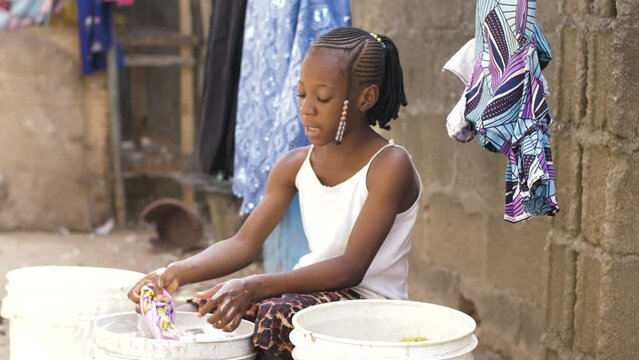 9 jan. 2024,Gwalada,Nigeria: African black girl  living in a rural villages washing her clothes in rural village settlement, villagers uses river stream water for washing by hand