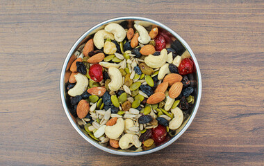 Trail mix nuts and seeds in a plate on wooden background top view 