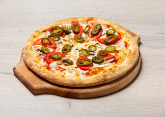 Mexican pizza with jalapenos, tomatoes, mushrooms and cheese on a wooden board
