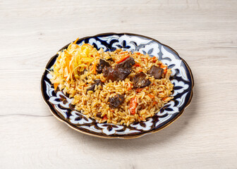 Uzbek pilaf on a traditional plate on a wooden background