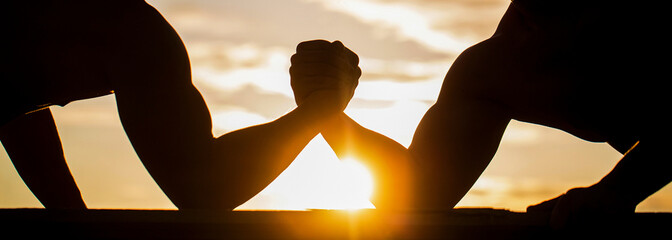 Rivalry, closeup of male arm wrestling. Sunset, sunrise. Men measuring forces, arms. Two men arm...