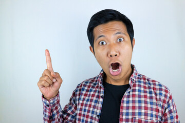 funny facial expression of asian man shocked and surprised while pointing at up side