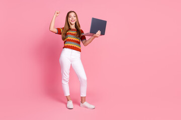 Full size photo of overjoyed nice person hold netbook raise fist success empty space isolated on pink color background