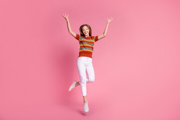 Full length photo of overjoyed lovely person jumping raise hands empty space isolated on pink color...