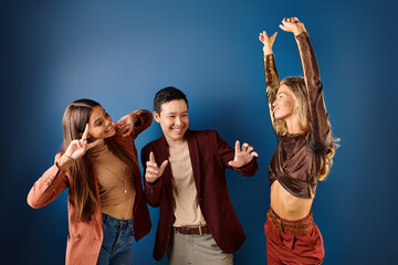 joyous interracial teenage friends in fashionable clothes having fun on dark blue background