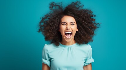 Cheerful young lady shouting happily while celebrating success against blue background - obrazy, fototapety, plakaty