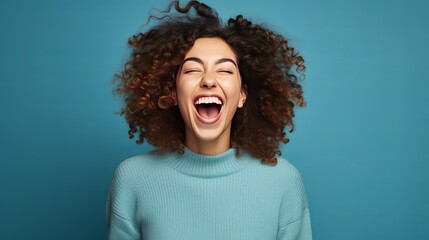 Cheerful young lady shouting happily while celebrating success against blue background