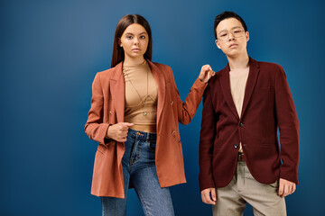elegant multiracial adolescents in stylish attires posing together on blue backdrop, friendship day