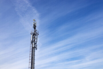 Obraz premium A tower telecommunications tower with antennas, against a background of blue sky with light clouds