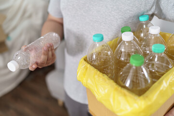 Home recycle eco green zero concept Man throwing empty plastic bottle in recycling bin with yellow garbage bags at home