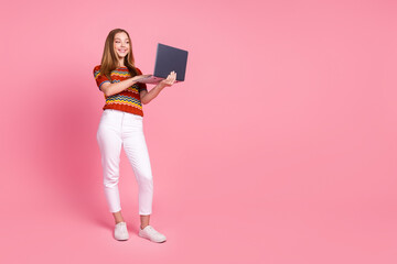 Full length photo of nice positive person hold laptop chatting communicate empty space isolated on pink color background