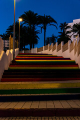Colorful stairs illuminated in a park at night in Nerja, Spain. Palm trees above the stairs.