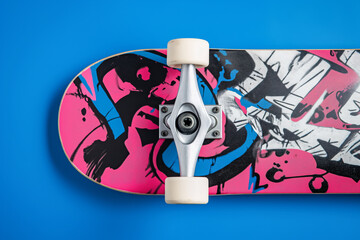 Skateboard with retro graffiti decal and white wheels on a blue background