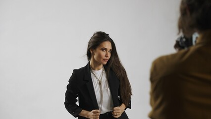Backstage of model and professional team in the studio. Close up of brunette model in suit posing,...
