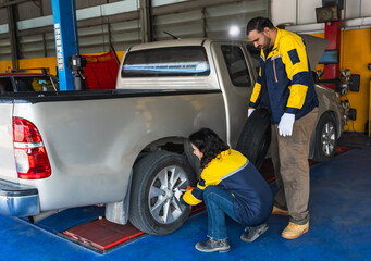 Car mechanic woman changing car tire with teammate man in auto tire repair shop