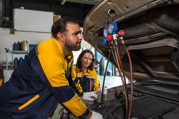 Male car mechanic checking air condition system working in auto repair workshop with female...