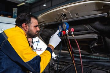 Male car mechanic checking car engine in auto repair shop