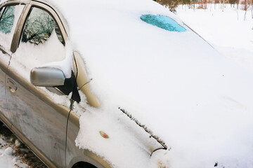 Snowy commuter car, gray car covered with snow.