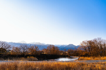 重光の池と冠雪した山岳風景　