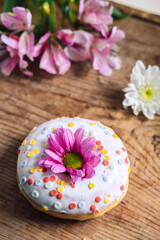 Obraz na płótnie Canvas chamomile bud on top of a donut on a wooden background with a bouquet of alstroemerias. Delicate frame with pink flower