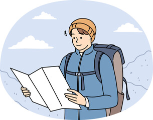 Young man in outerwear hiking in mountains check paper map for directions. Smiling male traveler or backpacker trekking in winter highlands.