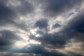 Ray of sun or sunbeam shining through the cloudy cumulus clouds floating in the skies, White grey...