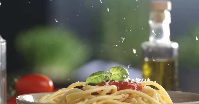 Super slow motion macro of a professional chef grating traditional parmesan cheese on traditional Italian dish of pasta spaghetti with red tomato sauce in restaurant kitchen at 1000 fps.