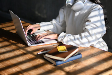 Woman wearing white shirt typing work on laptop on desk