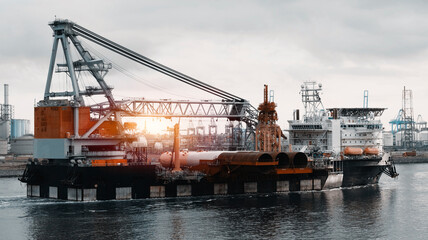 Fototapeta premium Wind Generators And Offshore Construction Crane Vessel With The Cargo Of Monopiles On Deck. Ship With Motion Compensated Pile Gripper And 8-point Anchor Mooring System