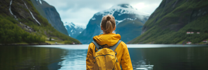 Young female hiker with a backpack admiring scenic view of spectacular Norwegian nature. Breathtaking landscape of Norway. Hiking by foot. - obrazy, fototapety, plakaty
