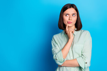 Portrait of suspicious girl with stylish hairdo wear turquoise blouse thoughtfully look empty space isolated on blue color background