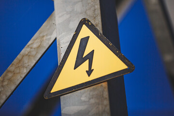 Close-up of a yellow Danger sign on a high-voltage line pole.