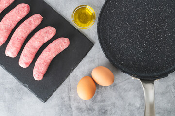 Fresh raw bratwurst (pork sausages), eggs, olive oil close-up on a kitchen table
