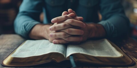 Man praying hands clasped together on Bible
