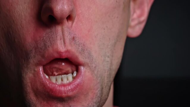 Man chewing food in slow motion close-up on a black background. The face of a man enjoying food. The person chews slowly.