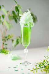 Glass of green champagne with cotton candy on the table. St. Patrick's Day Concept