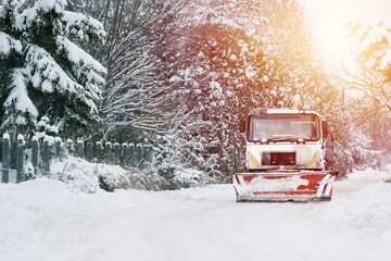 Orange truck removes snow. Snow plow on highway salting road. Tractor performing street deicing.